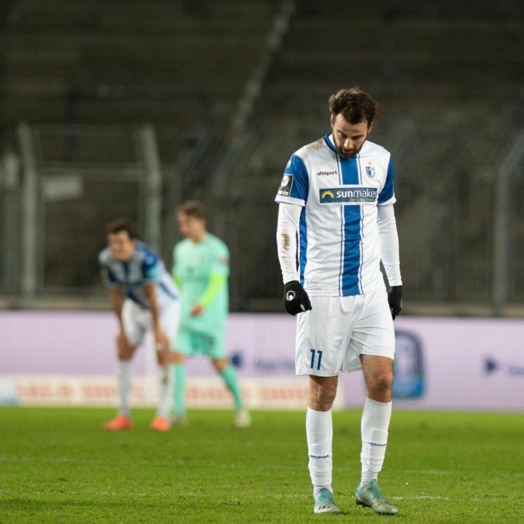 Christian Beck steht mit gesenktem Haupt auf dem Platz